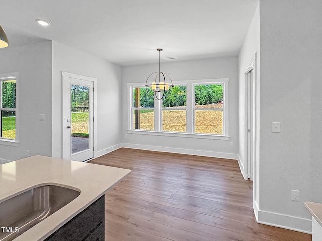 unfurnished dining area with plenty of natural light, baseboards, a chandelier, wood finished floors, and recessed lighting