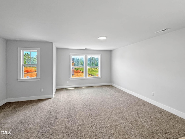 carpeted spare room featuring plenty of natural light and baseboards
