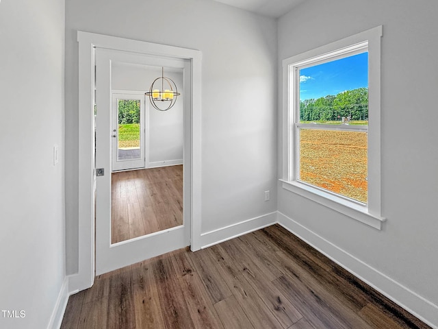 foyer entrance with a chandelier, dark wood-type flooring, healthy amount of natural light, and baseboards