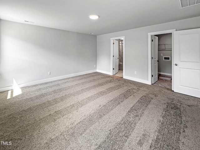 unfurnished bedroom featuring baseboards, carpet flooring, a walk in closet, and connected bathroom