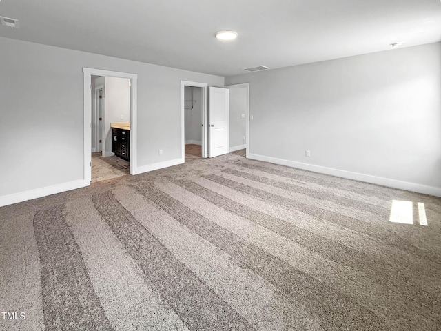 unfurnished bedroom with baseboards, carpet, a walk in closet, and connected bathroom