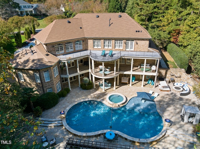 exterior space featuring a balcony, a patio, and a pool with hot tub