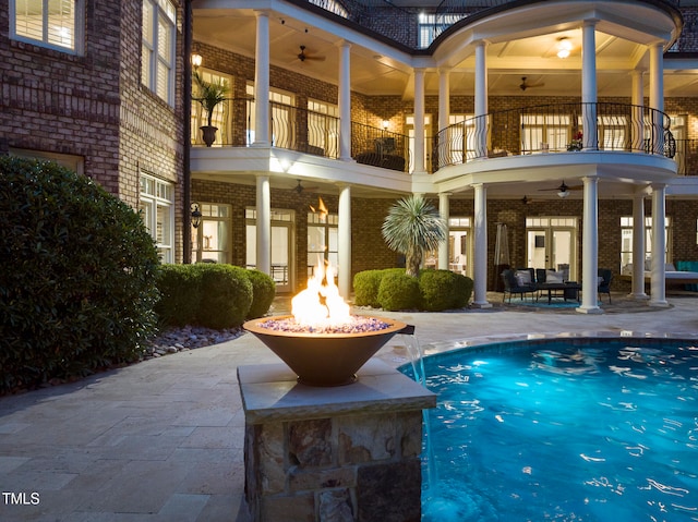 view of pool with pool water feature, ceiling fan, a fire pit, and a patio area