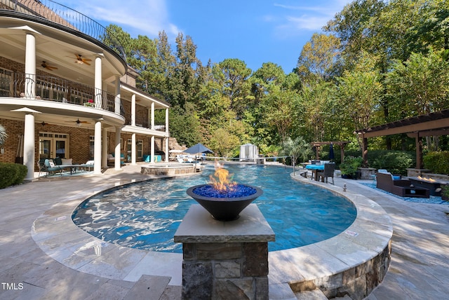 view of pool featuring an in ground hot tub, pool water feature, ceiling fan, a fire pit, and a patio area