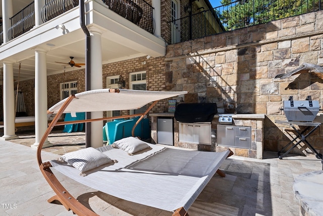 view of patio with a balcony, area for grilling, ceiling fan, and exterior kitchen