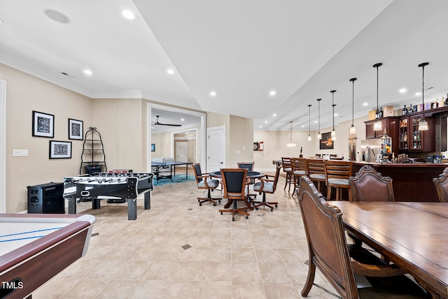 dining room with bar area, ceiling fan, light tile patterned floors, and ornamental molding