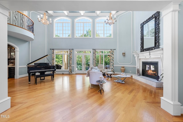 living room featuring crown molding, french doors, wood-type flooring, and a notable chandelier