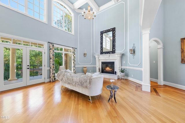 living room with a high ceiling, ornate columns, french doors, and wood-type flooring