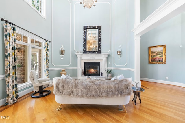 sitting room with hardwood / wood-style flooring, plenty of natural light, and a towering ceiling