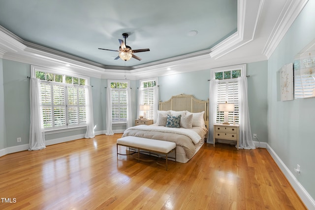 bedroom featuring ceiling fan, light hardwood / wood-style floors, ornamental molding, and a tray ceiling