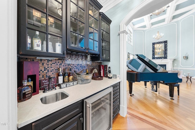 bar with sink, hanging light fixtures, coffered ceiling, wine cooler, and light hardwood / wood-style floors