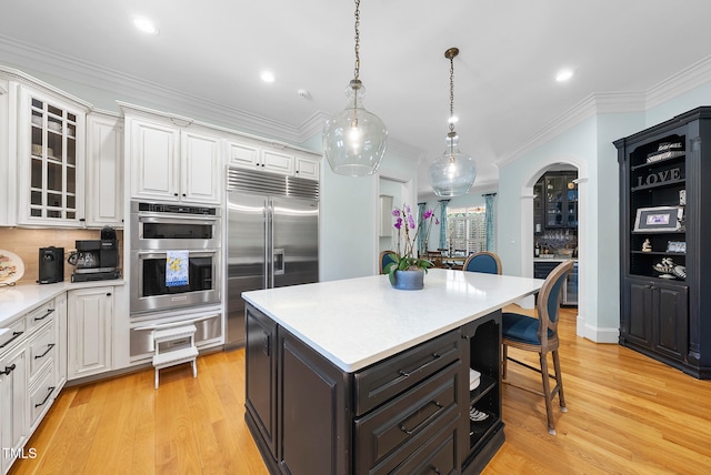 kitchen featuring a center island, white cabinets, stainless steel appliances, and light wood-type flooring