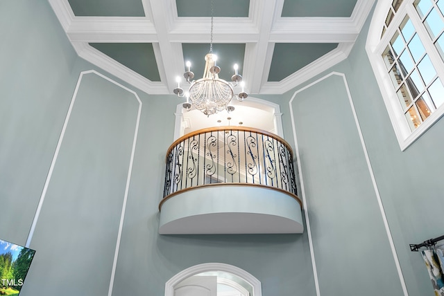 staircase featuring an inviting chandelier, a wealth of natural light, coffered ceiling, and crown molding