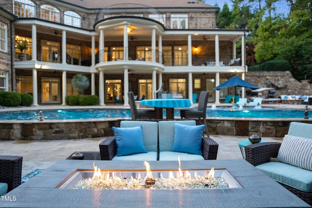 rear view of house with a fire pit, a patio area, and a balcony