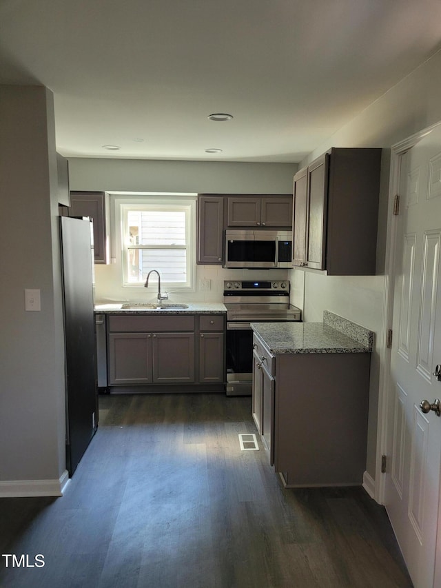 kitchen featuring light stone countertops, sink, appliances with stainless steel finishes, and dark hardwood / wood-style flooring