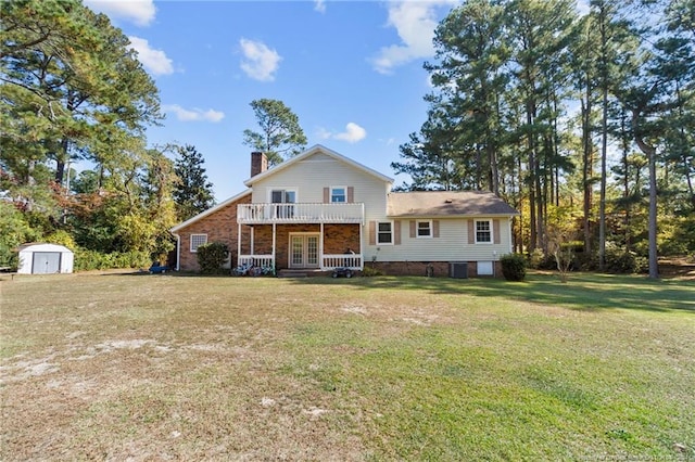 view of front facade with a balcony, a front lawn, and a storage shed