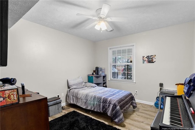 bedroom with ceiling fan, a textured ceiling, and light wood-type flooring