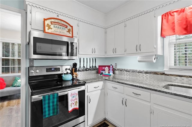 kitchen featuring appliances with stainless steel finishes, ornamental molding, sink, stone counters, and white cabinets