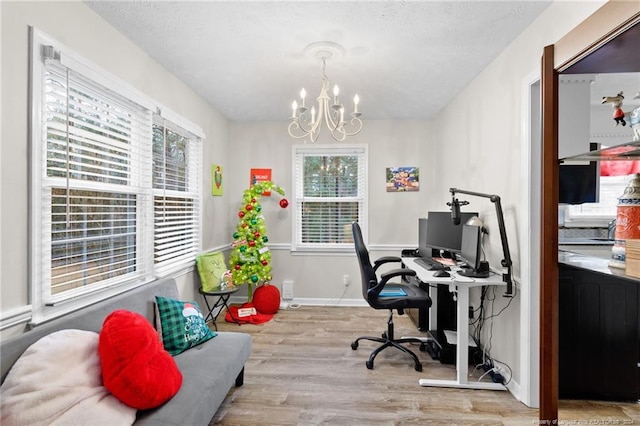 home office featuring a notable chandelier, plenty of natural light, and light wood-type flooring