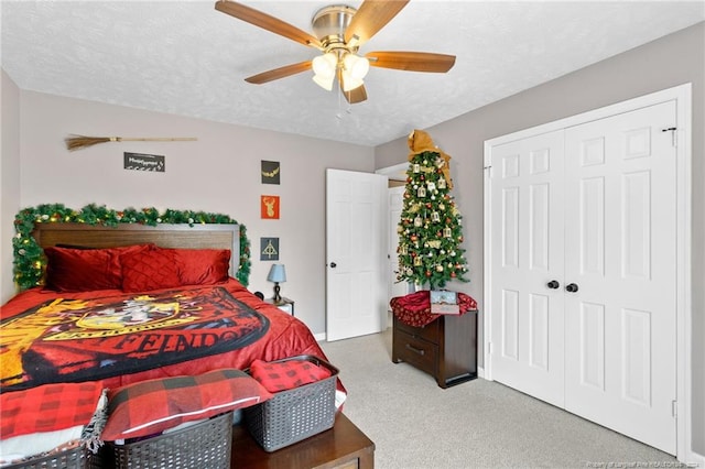 bedroom with a textured ceiling, a closet, ceiling fan, and light colored carpet