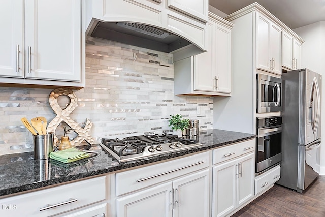 kitchen featuring appliances with stainless steel finishes, white cabinets, dark wood-type flooring, and backsplash