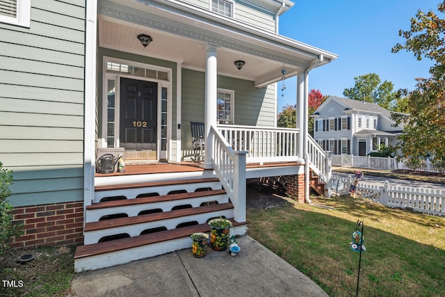 entrance to property featuring covered porch and a lawn