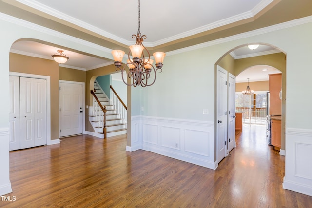 empty room featuring ornamental molding, dark wood-type flooring, and a chandelier