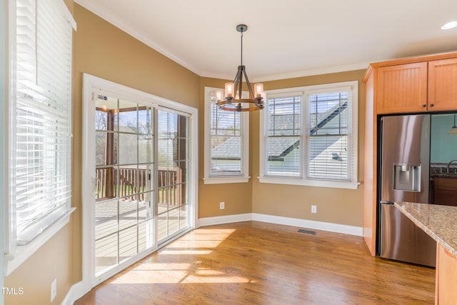 unfurnished dining area with an inviting chandelier, light hardwood / wood-style flooring, and ornamental molding