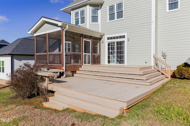 back of property featuring a deck, a lawn, and a sunroom