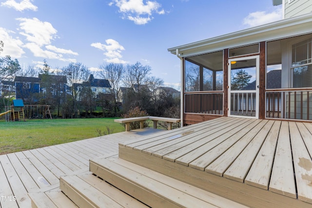 wooden deck featuring a playground, a sunroom, and a lawn