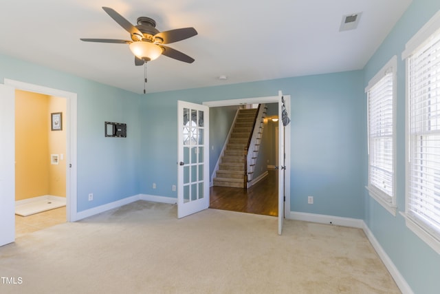 spare room featuring a wealth of natural light, french doors, and light colored carpet