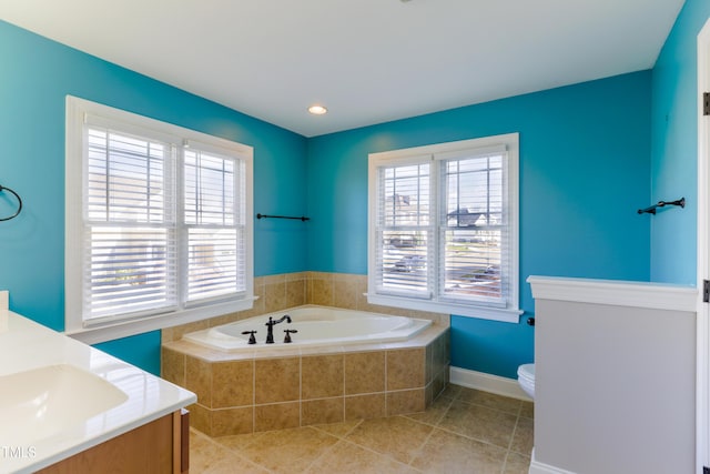 bathroom with toilet, tile patterned flooring, vanity, and a relaxing tiled tub