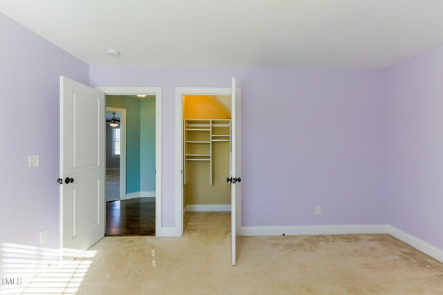 unfurnished bedroom featuring a closet, light colored carpet, and a spacious closet