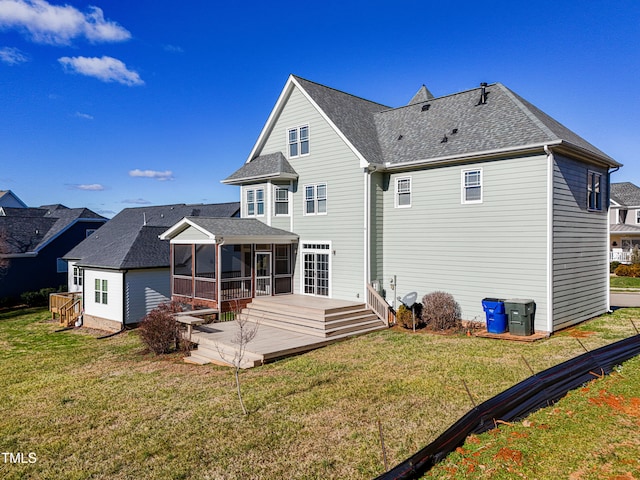 rear view of property featuring a lawn, a deck, and a sunroom