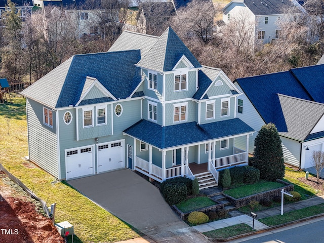 view of front facade with covered porch, a garage, and a front lawn