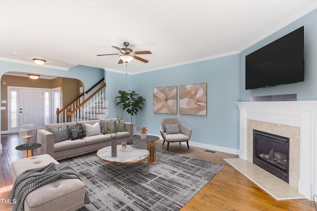 living room with ceiling fan, hardwood / wood-style flooring, crown molding, and a fireplace