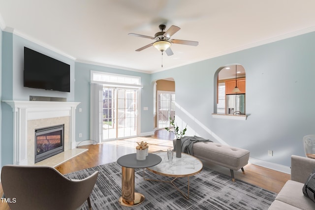 living room with a high end fireplace, a wealth of natural light, wood-type flooring, and ornamental molding