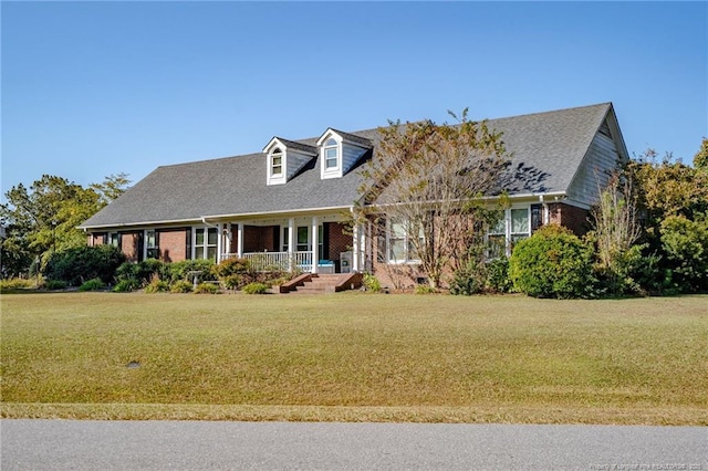 cape cod home featuring a front yard, a porch, and brick siding