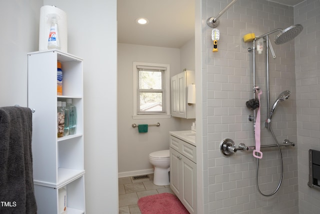 bathroom with a tile shower, toilet, tile patterned flooring, and vanity