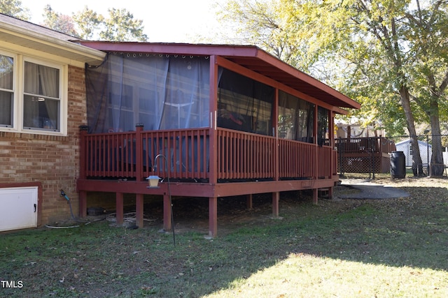 view of home's exterior with a wooden deck, a yard, and a sunroom