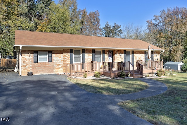 ranch-style house with covered porch, a front yard, and an outbuilding