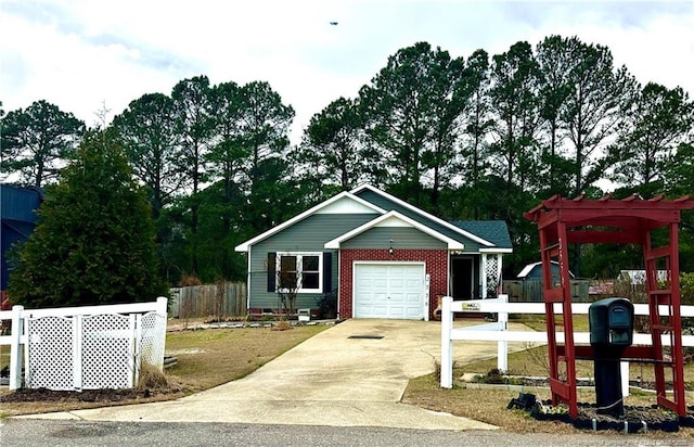 view of front of home with driveway, brick siding, an attached garage, and fence