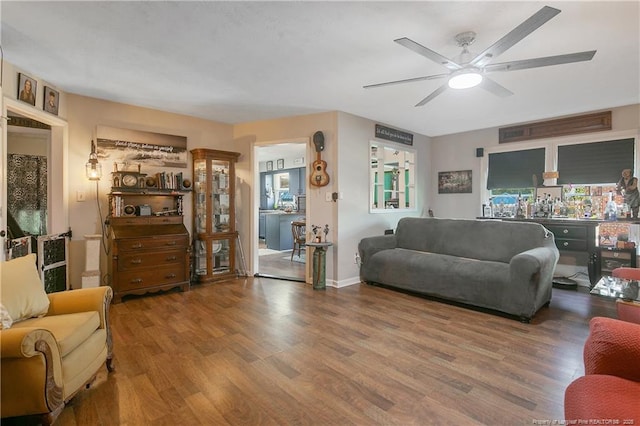 living room featuring ceiling fan, baseboards, and wood finished floors