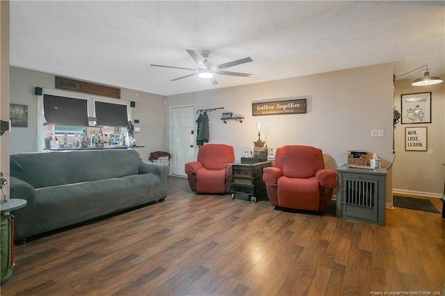 living area featuring a ceiling fan, baseboards, and wood finished floors