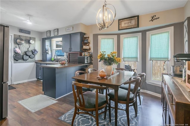 dining area with dark wood finished floors, baseboards, and an inviting chandelier