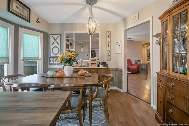 dining room with a wainscoted wall, a chandelier, and wood finished floors