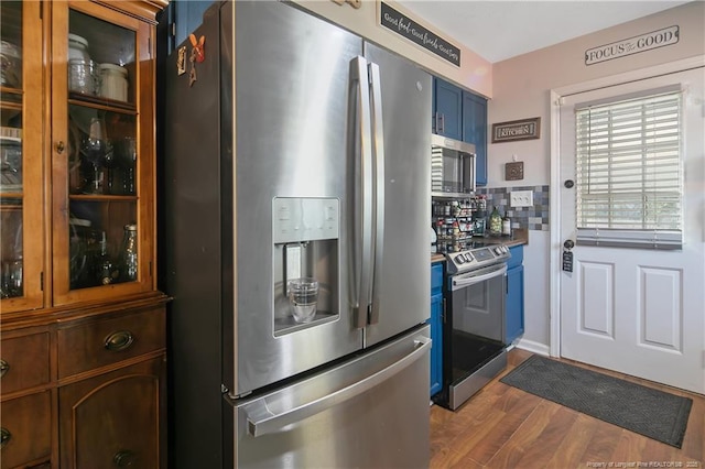 kitchen featuring tasteful backsplash, appliances with stainless steel finishes, glass insert cabinets, dark wood-type flooring, and blue cabinets