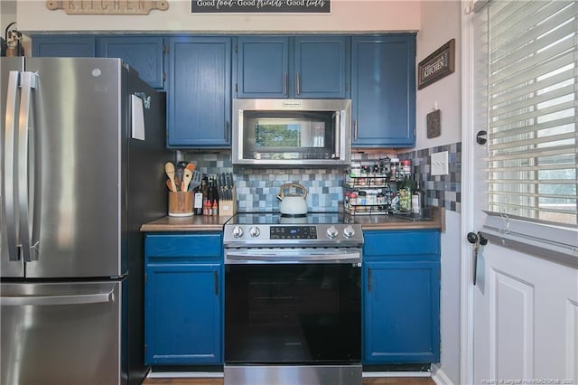 kitchen with blue cabinets, dark countertops, tasteful backsplash, and stainless steel appliances