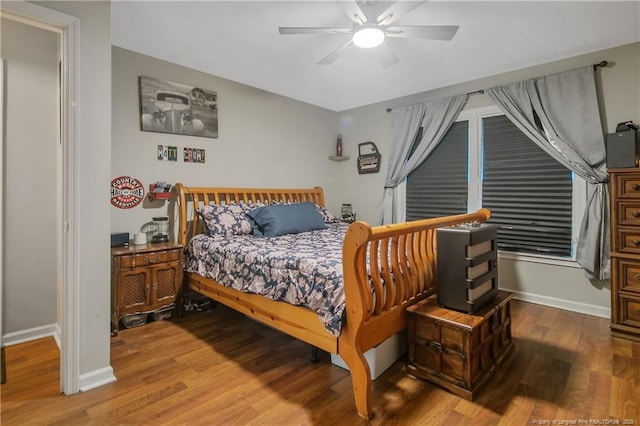 bedroom with a ceiling fan, baseboards, and wood finished floors