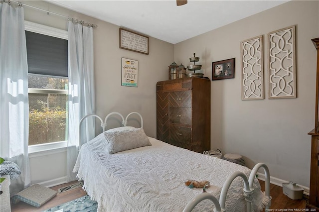 bedroom with wood finished floors, visible vents, and baseboards